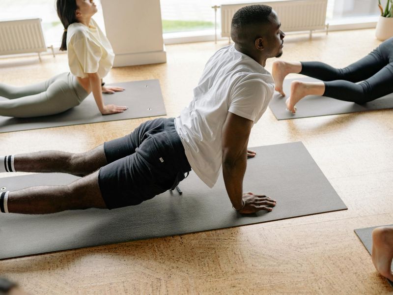Man stretching on a yoga mat in a modern, well-lit room.